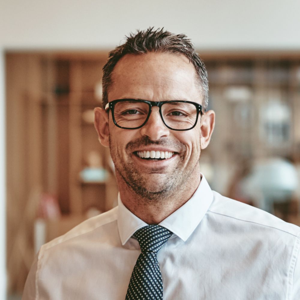 smiling-mature-businessman-standing-alone-in-an-of-Y89VGBD-1-1.jpg